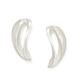 These angel twist earrings in silver are like curved wings with white recesses to contrast the polished surfaces and accentuate the design. Angel twist earrings by Sarah Herriot.