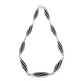 This striking neckpiece in silver showcases an inventive architectural approach to contemporary jewellery design, composed of linked twisted forms, the piece uses linear deconstruction to create visual rhythm and movement. Beat twist neck piece by Sarah Herriot.