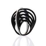 The double crane ring in silver is a linear construction on flowing and crossing wires that create a stunning sculptural form , the black plate help to accentuate the design. Double crane ring by Sarah Herriot.