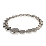 The escalator neckpiece shows geometric abstraction through its precisely offset tapering disc construction, the gently undulating surfaces create a dynamic interplay of light, while the oxidised recesses articulate the linear deconstructed form. Escalator neckpiece by Sarah Herriot.
