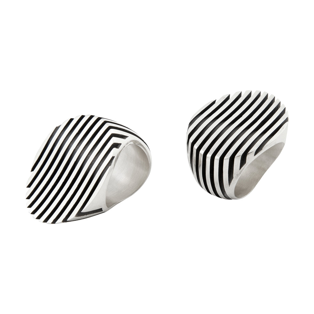Escalator ring is a clever design formed of spaced sheets of silver with a gently undulating surface where the oxidised recesses accentuate the form. An abstract form with linear deconstruction.  Escalator ring by Sarah Herriot.