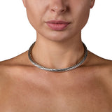 A solid silver torque featuring an abstract rhythmic linear pattern dancing across the surface, the ultimate in understated elegance, with a seamless tension clasp. This timeless piece combines technical precision with minimalist design, offering effortless wearability without compromising on craftsmanship. Jazz tension torque by Sarah Herriot.