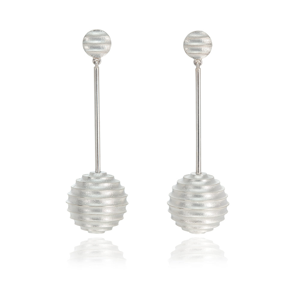 Lunar earrings, studs fitting with an elegant long drop finished with a hollow sphere formed of an undulating texture in brushed silver.  Lunar earrings by Sarah Herriot.