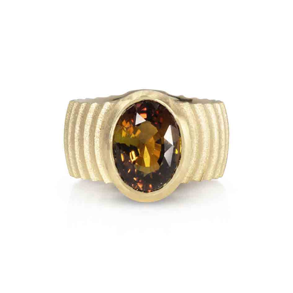 Lunar ring with undulating textured 18ct gold and set with a colour changing tourmaline showing amber gold and green. The design is based on the throwing of a ceramic pot, with the finger indentations up the walls, giving an almost planetary feel.  Lunar ring by Sarah Herriot.