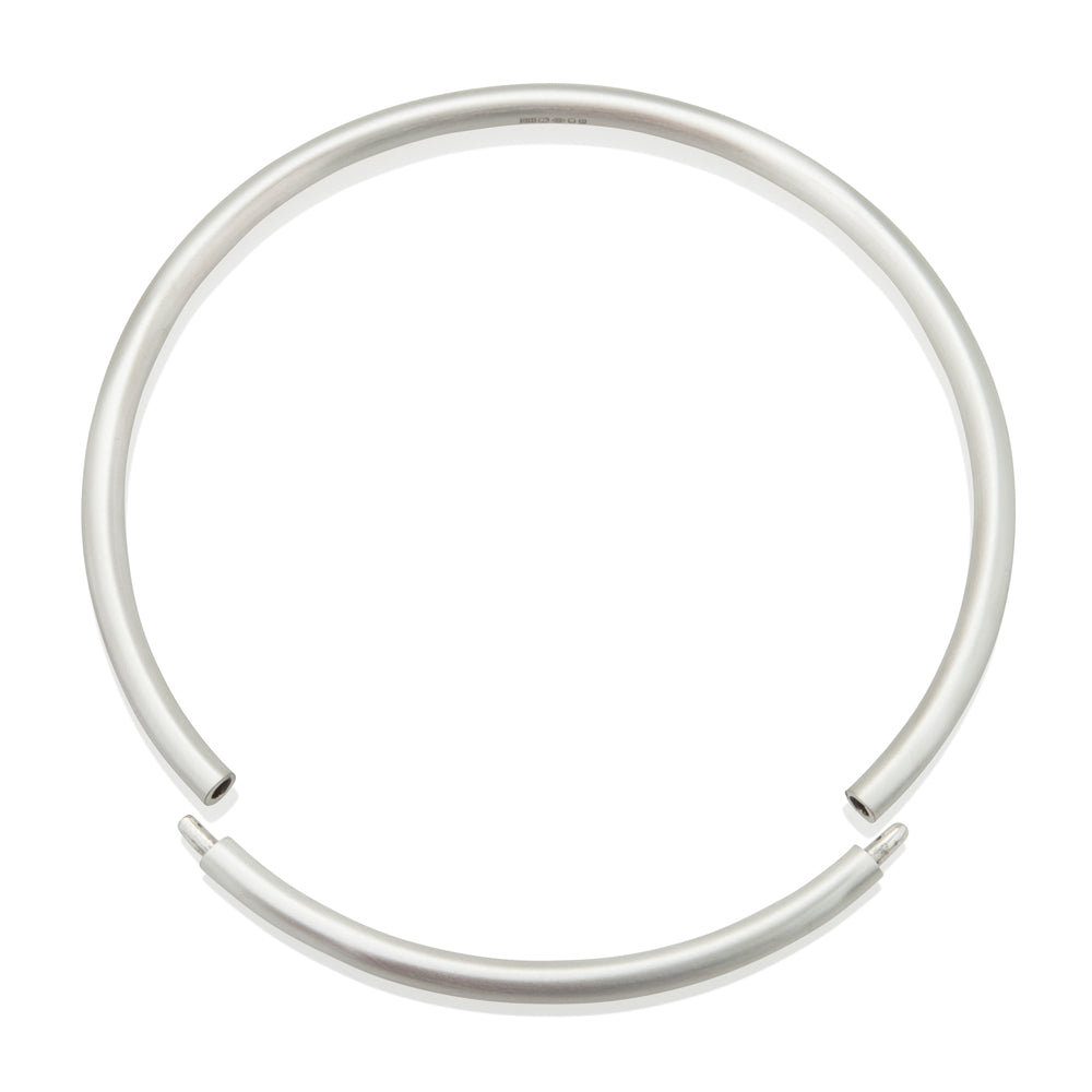 A solid silver torque featuring a seamless tension clasp, the ultimate in understated elegance. This timeless piece combines technical precision with minimalist design, offering effortless wearability without compromising on craftsmanshipTension neck torque by Sarah Herriot.