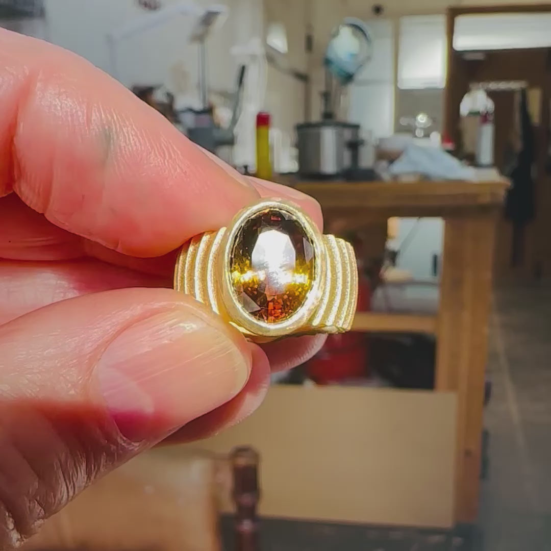 Lunar ring with undulating textured 18ct gold and set with a colour changing tourmaline showing amber gold and green. The design is based on the throwing of a ceramic pot, with the finger indentations up the walls, giving an almost planetary feel.  Lunar ring by Sarah Herriot.