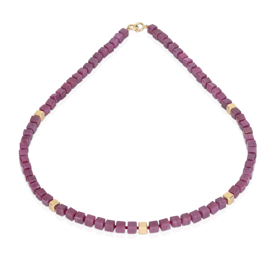 This necklace features elegant ruby and 18ct gold cubes with refined sophistication, creating a striking yet understated jewel. A masterwork of minimalist luxury that celebrates the natural beauty of ruby's opaque raspberry colour in combination with rich gold. through timeless architectural form. Ruby cube necklace by Sarah Herriot.