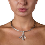 Splash neckpiece in polished and sandblasted silver with rhodium plating on a nine strand steel neck wire by Sarah Herriot.