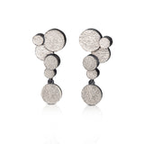 Staffa earrings are formed of undulating discs of silver with a deep textured surface and a blackened edge.  Staffa earrings by Sarah Herriot.