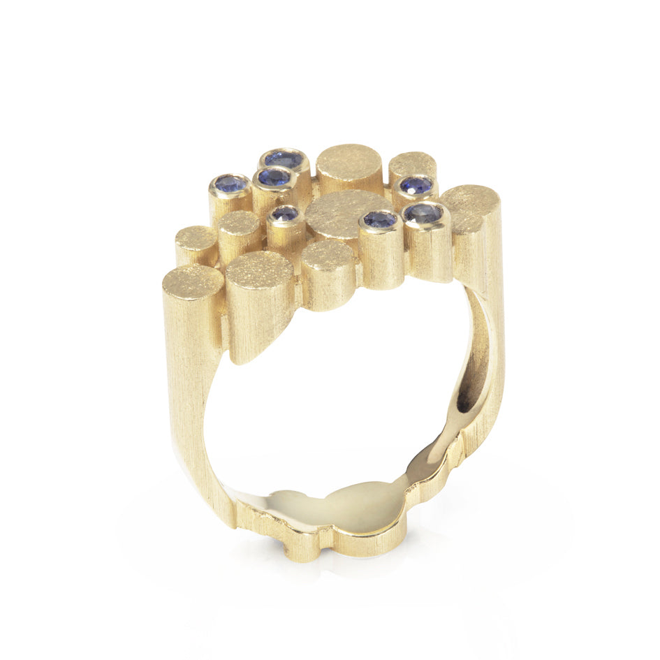Staffa ring formed of undulating columns of 18ct gold and a scattering of seven vibrant blue Sri Lankan sapphires. The design is inspired by fingal's cave on the isle of staffa off the west coast of Scotland. Textured surfaces echo the natural basalt rock formations. Staffa reing by Sarah Herriot.