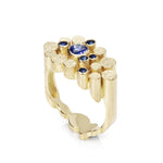 Staffa ring formed of undulating columns of 18ct gold and a scattering of seven vibrant blue Sri Lankan sapphires. The design is inspired by fingal's cave on the isle of staffa off the west coast of Scotland. Textured surfaces echo the natural basalt rock formations. Staffa reing by Sarah Herriot.