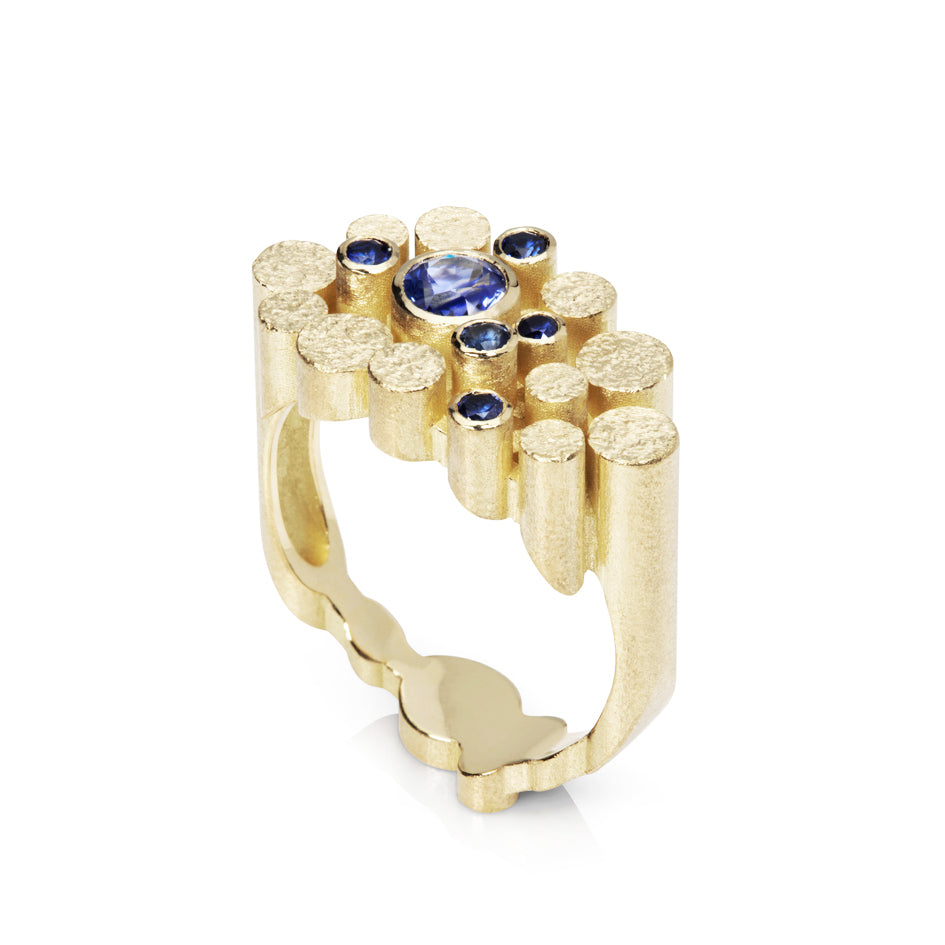 Staffa ring formed of undulating columns of 18ct gold and a scattering of seven vibrant blue Sri Lankan sapphires. The design is inspired by fingal's cave on the isle of staffa off the west coast of Scotland. Textured surfaces echo the natural basalt rock formations. Staffa reing by Sarah Herriot.