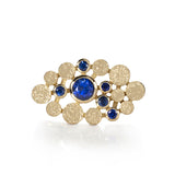 Staffa ring formed of undulating columns of 18ct gold and a scattering of seven vibrant blue Sri Lankan sapphires. The design is inspired by fingal's cave on the isle of staffa off the west coast of Scotland. Textured surfaces echo the natural basalt rock formations. Staffa reing by Sarah Herriot.