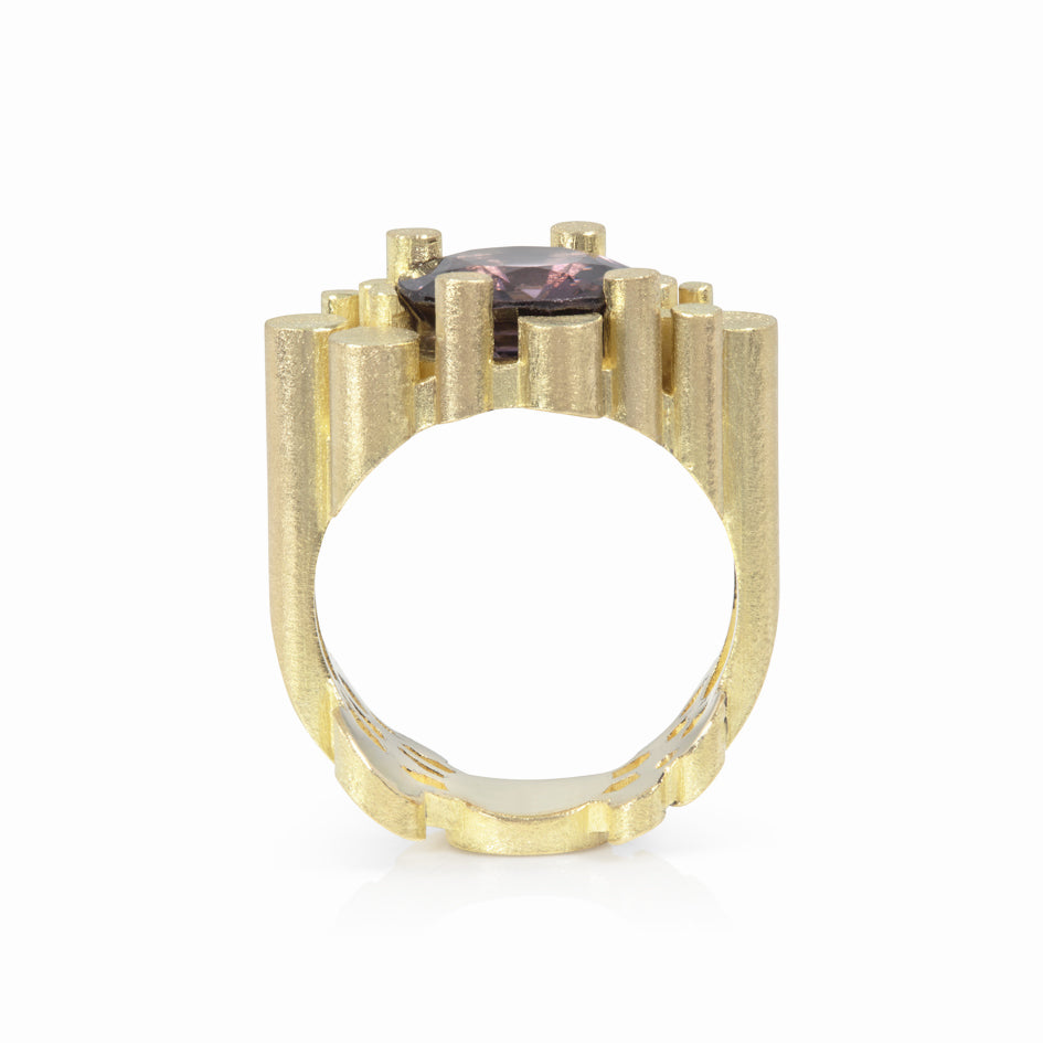 Staffa ring formed of  undulating columns of 18ct gold and a moody sparkly cushion violet spinel nestled within.  Staffa ring by Sarah Herriot.