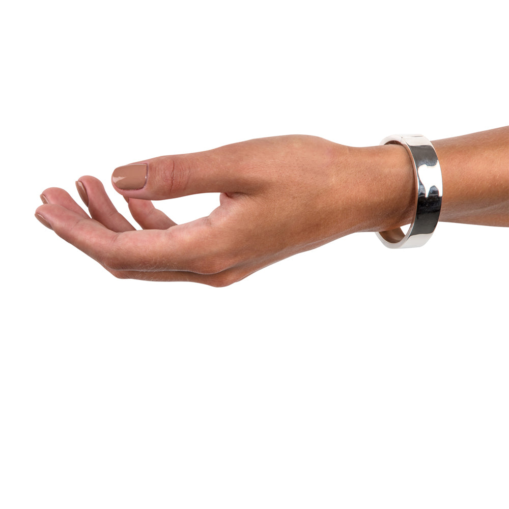 A masterfully engineered solid silver bangle with a seamless tension clasp that requires no visible mechanism. The rectangular-section wire creates a refined, sculptural form that sits beautifully on the wrist with an authentic weight and presence. Seamless design embodies minimalist principles, pure form without ornamentation.  Tension bangle by Sarah Herriot.