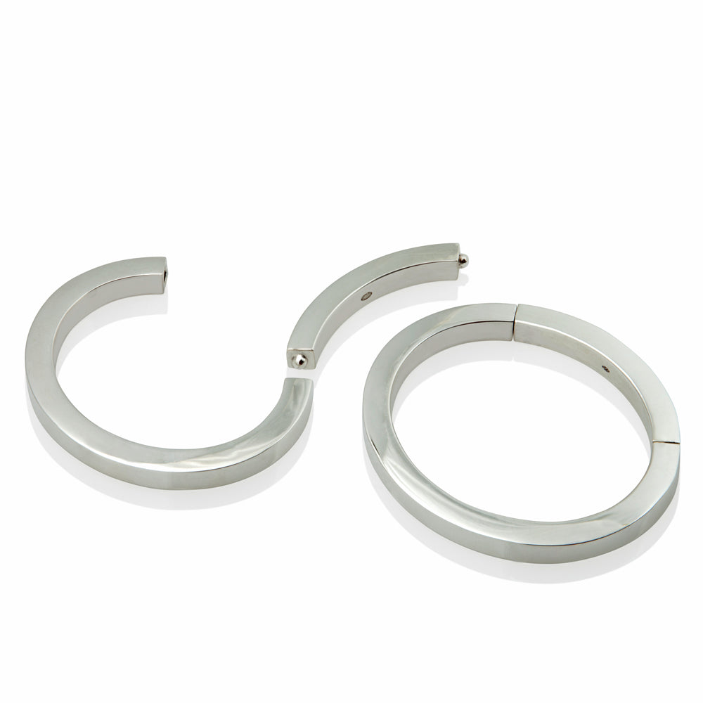 A masterfully engineered solid silver bangle with a seamless tension clasp that requires no visible mechanism. The square-section wire creates a refined, sculptural form that sits beautifully on the wrist with an authentic weight and presence. Seamless design embodies minimalist principles, pure form without ornamentation.  Tension bangle by Sarah Herriot.